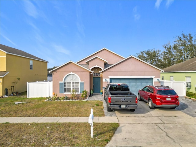 view of front of property featuring a garage, a front yard, fence, and stucco siding