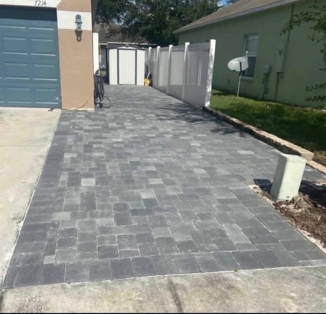 exterior space featuring a garage, an outbuilding, fence, and a storage unit