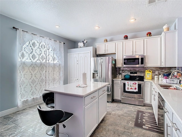 kitchen featuring stainless steel appliances, a kitchen bar, a sink, and light countertops