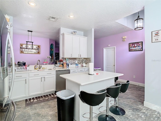 kitchen with stainless steel appliances, light countertops, visible vents, white cabinets, and a sink