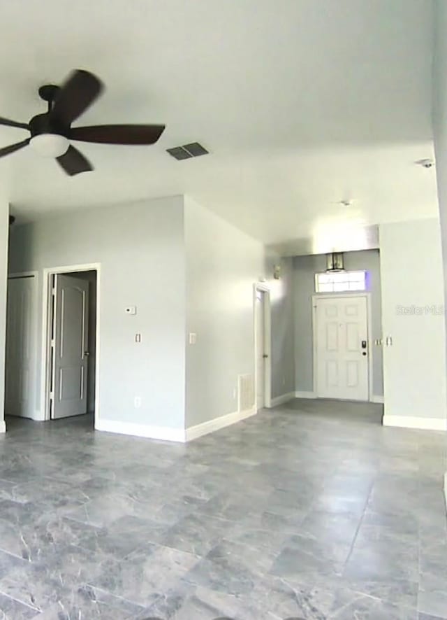 empty room with ceiling fan, visible vents, and baseboards