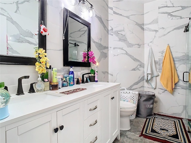 full bathroom featuring double vanity, a stall shower, a sink, and toilet