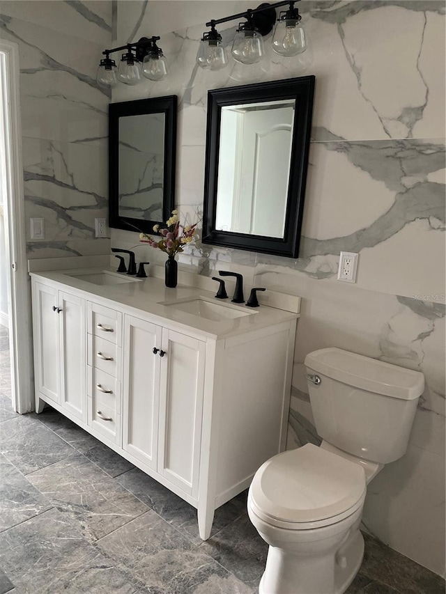 bathroom with a sink, tile walls, toilet, and double vanity