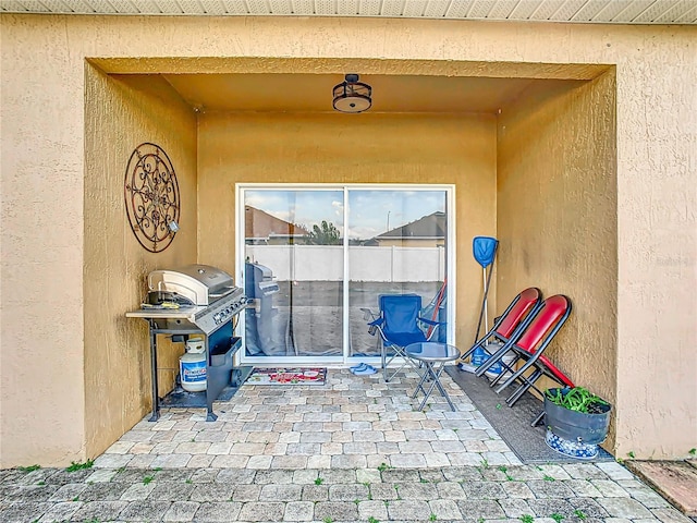 view of exterior entry featuring a patio area and stucco siding