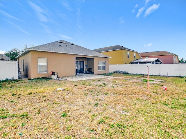 rear view of property featuring a fenced backyard, a lawn, and a patio