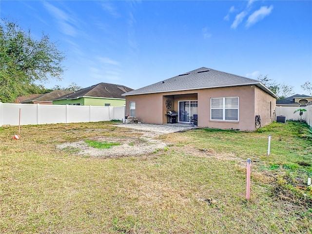 back of property featuring a yard, central AC unit, fence, and stucco siding