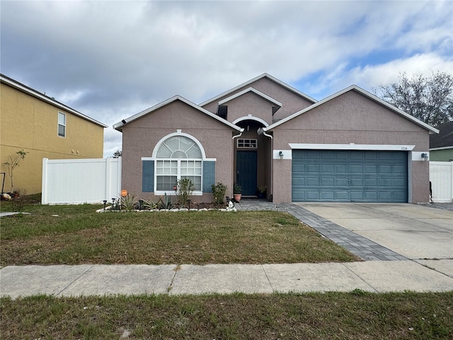 ranch-style home with an attached garage, fence, a front lawn, and stucco siding