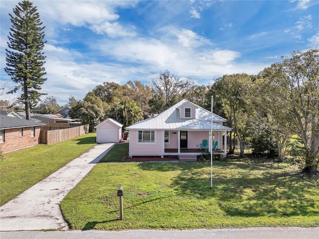 view of front of home featuring an outbuilding, a garage, covered porch, and a front lawn