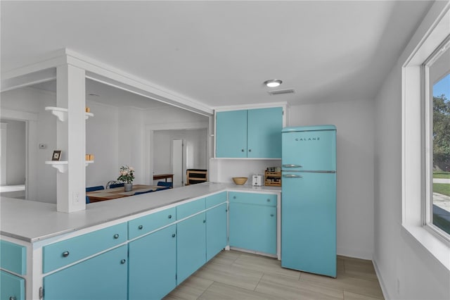 kitchen with blue cabinets, refrigerator, and kitchen peninsula