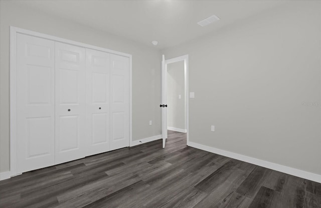 unfurnished bedroom featuring dark hardwood / wood-style flooring and a closet