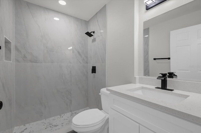 bathroom with vanity, toilet, and tiled shower