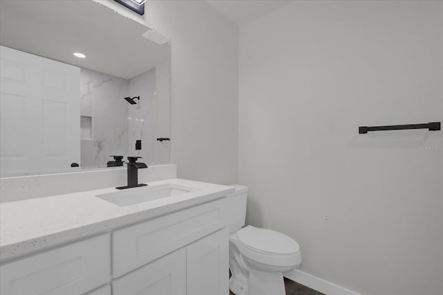 bathroom featuring tiled shower, vanity, and toilet