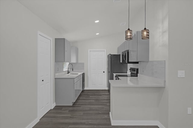 kitchen with dark wood-type flooring, sink, tasteful backsplash, appliances with stainless steel finishes, and pendant lighting