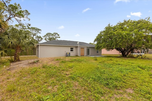 rear view of house with cooling unit and a yard