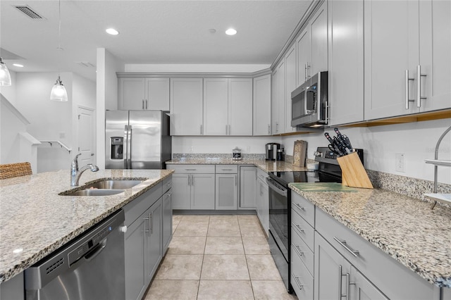 kitchen featuring light stone counters, stainless steel appliances, gray cabinets, and sink