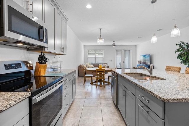 kitchen featuring stainless steel appliances, sink, a center island with sink, and gray cabinetry