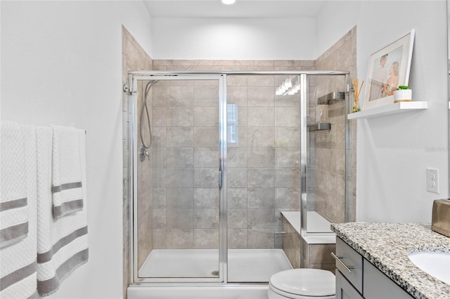 bathroom featuring vanity, toilet, and a shower with shower door