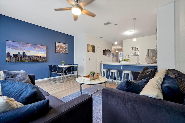 living room featuring ceiling fan and light hardwood / wood-style flooring