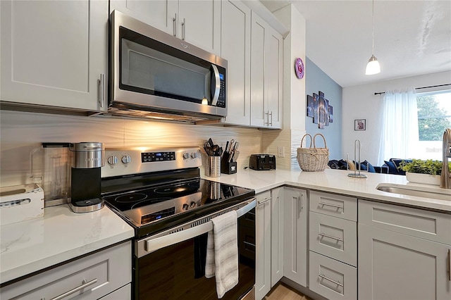 kitchen featuring pendant lighting, sink, decorative backsplash, stainless steel appliances, and light stone countertops