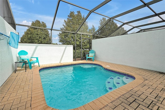 view of swimming pool featuring a patio and glass enclosure