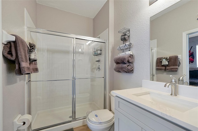 bathroom featuring vanity, an enclosed shower, and toilet