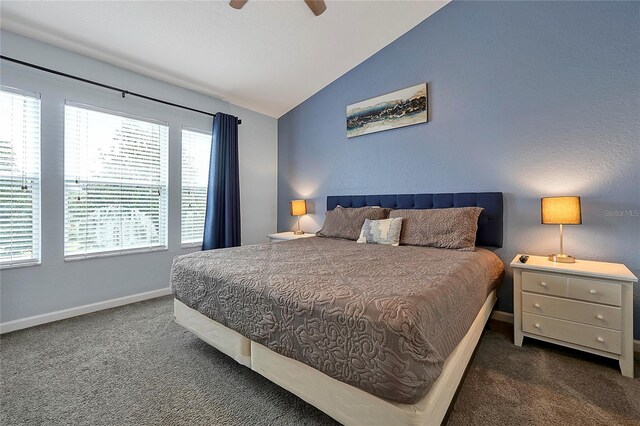 bedroom with ceiling fan, vaulted ceiling, and dark colored carpet