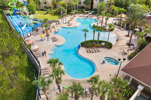 view of pool featuring a patio, a water slide, and a community hot tub