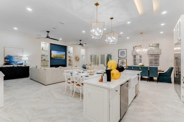 kitchen featuring pendant lighting, white cabinetry, a center island, ceiling fan with notable chandelier, and stainless steel dishwasher