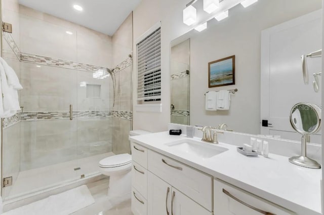 bathroom with vanity, a shower with door, and toilet