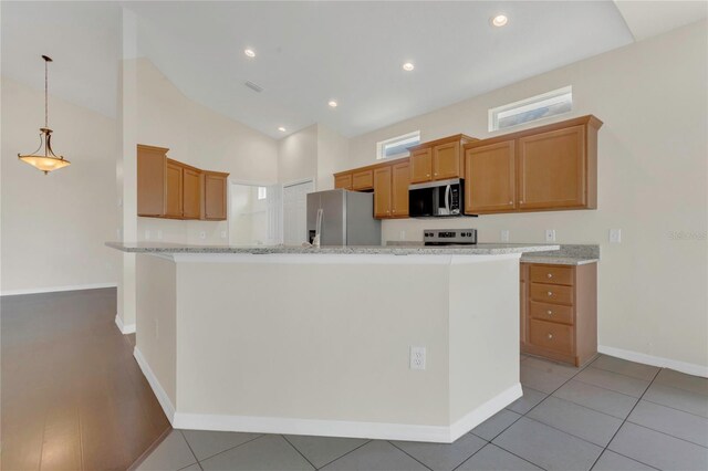 11530 57th Street Cir E, Parrish, FL 34219 - kitchen with stainless steel appliances, baseboards, brown cabinets, decorative light fixtures, and light tile patterned flooring
