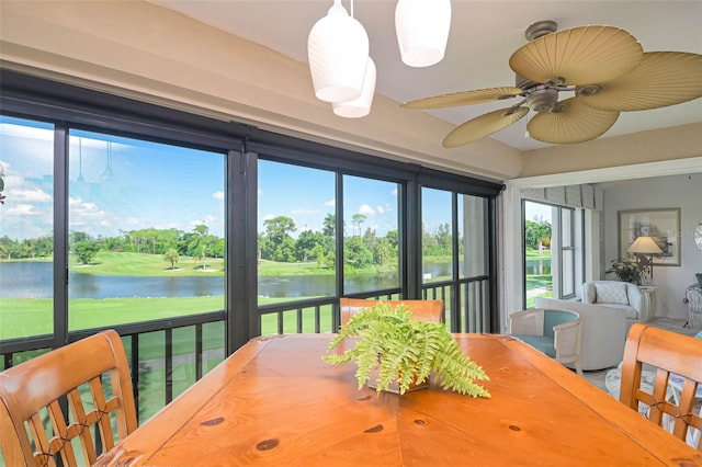 sunroom with ceiling fan and a water view