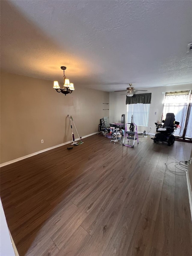 unfurnished living room with hardwood / wood-style flooring, ceiling fan with notable chandelier, and a textured ceiling