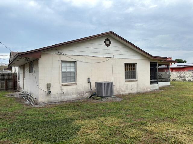 back of house with central AC unit and a yard