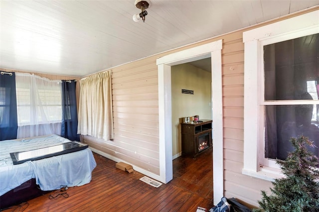 bedroom featuring wooden walls and dark hardwood / wood-style floors