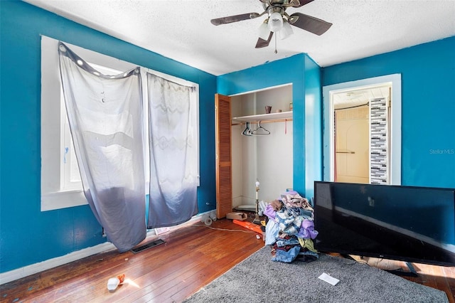 unfurnished bedroom with ceiling fan, dark wood-type flooring, a closet, and a textured ceiling