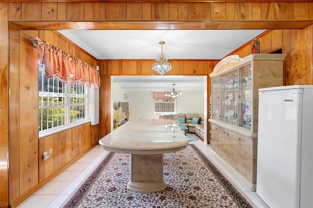 interior space with light tile patterned floors, a chandelier, and wood walls