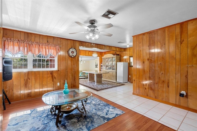 living room with ceiling fan, wooden walls, and light hardwood / wood-style flooring