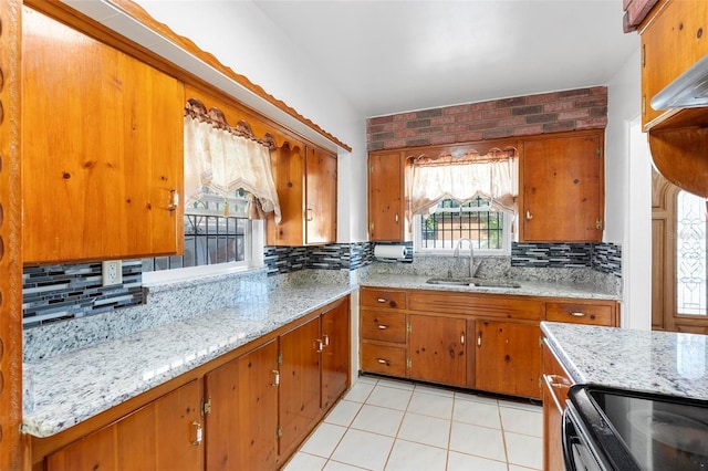 kitchen featuring light stone counters, light tile patterned flooring, sink, and decorative backsplash