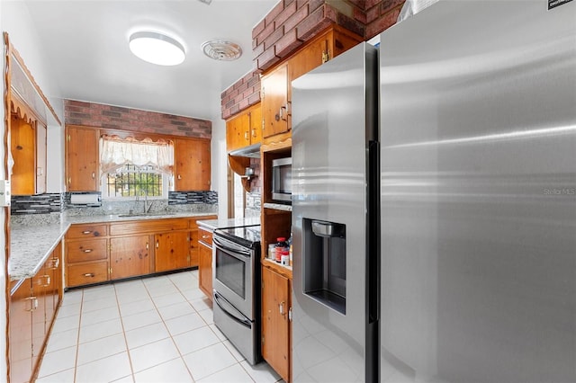 kitchen featuring sink, decorative backsplash, light tile patterned floors, stainless steel appliances, and light stone countertops