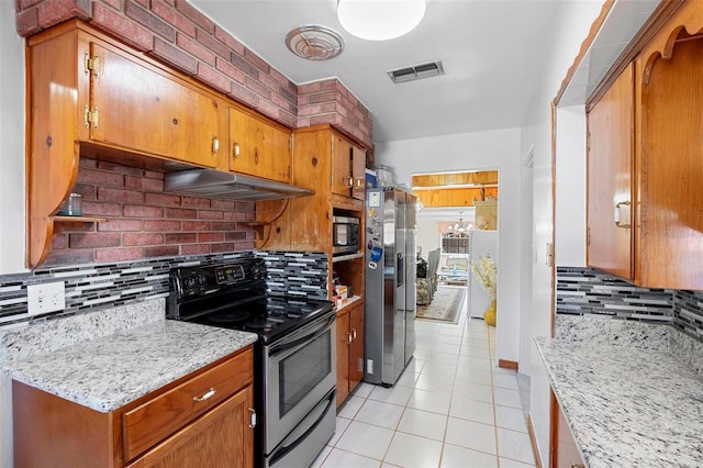 kitchen with tasteful backsplash, light stone countertops, stainless steel appliances, and light tile patterned flooring
