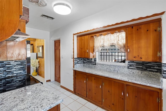 kitchen featuring backsplash, exhaust hood, black electric stovetop, light tile patterned floors, and light stone countertops