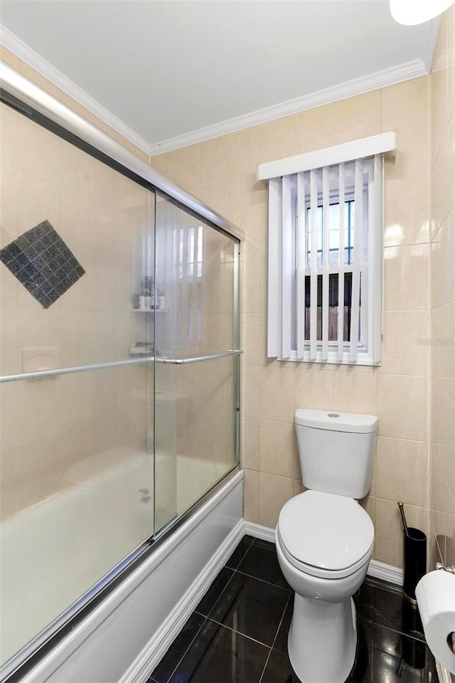 bathroom with ornamental molding, combined bath / shower with glass door, tile patterned floors, and toilet