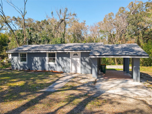 view of front of home featuring driveway, an attached carport, and a front lawn