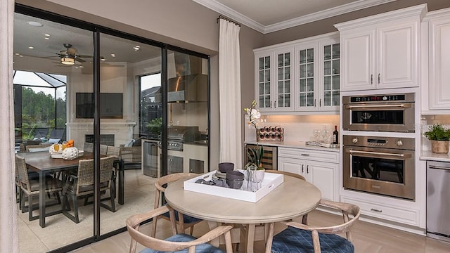 kitchen with wall chimney range hood, white cabinetry, stainless steel appliances, ornamental molding, and beverage cooler