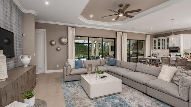 living room featuring ceiling fan, ornamental molding, and a tray ceiling