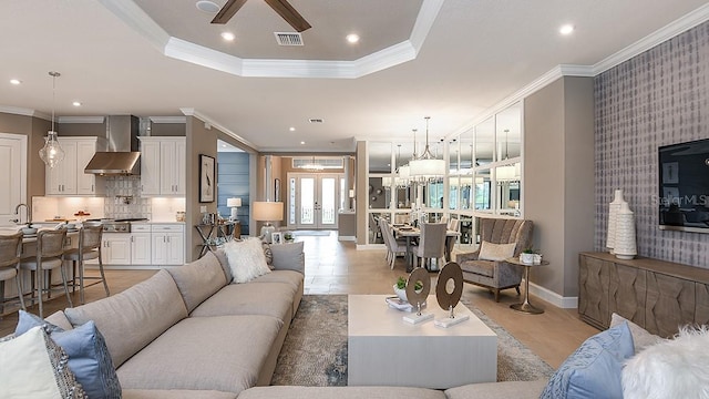 living room featuring french doors, sink, crown molding, a raised ceiling, and ceiling fan