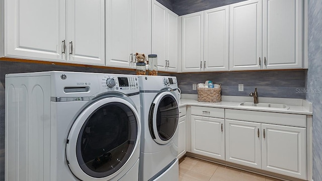 washroom with light tile patterned flooring, cabinets, washer and clothes dryer, and sink