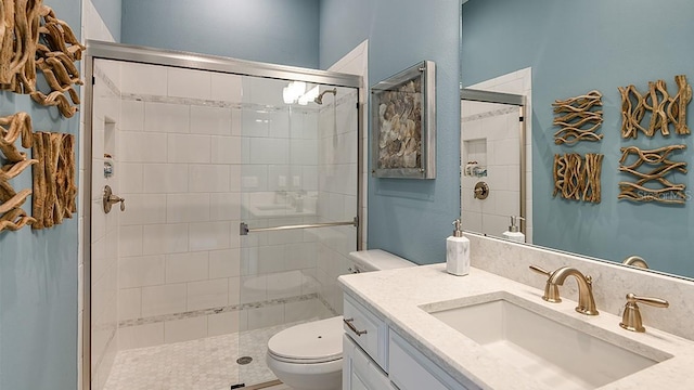 bathroom featuring vanity, a shower with door, and toilet