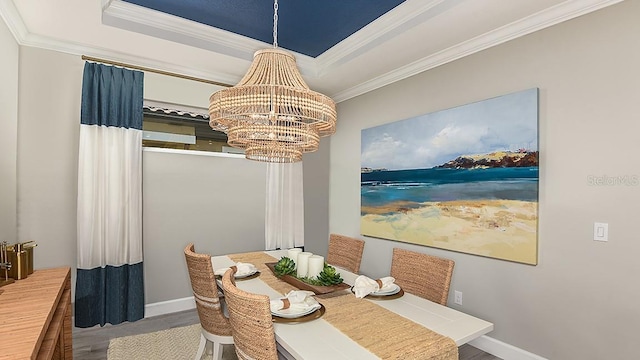 dining space featuring crown molding, hardwood / wood-style flooring, a raised ceiling, and a notable chandelier