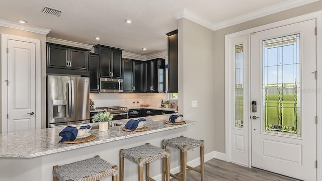 kitchen with light stone counters, a kitchen bar, kitchen peninsula, and appliances with stainless steel finishes